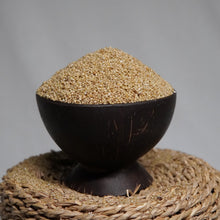 Load image into Gallery viewer, A dark bowl filled with Browntop millet, set on a woven natural-fiber pedestal against a soft gray background.
